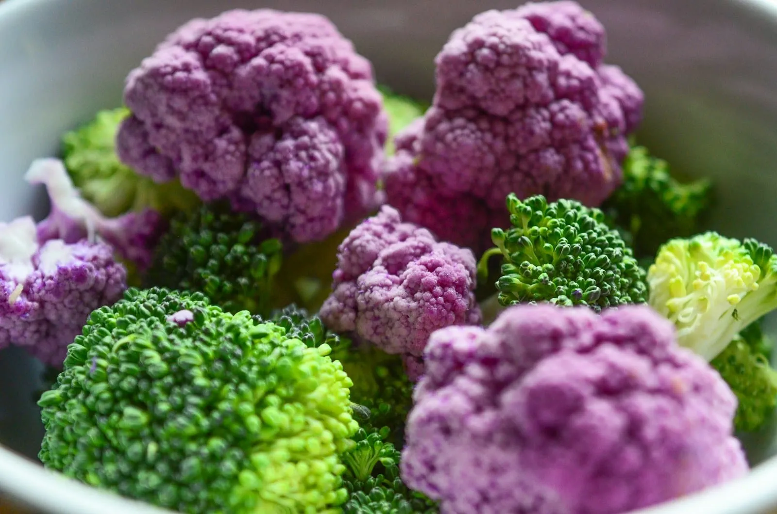 Purple cauliflower and broccoli florets packed together.