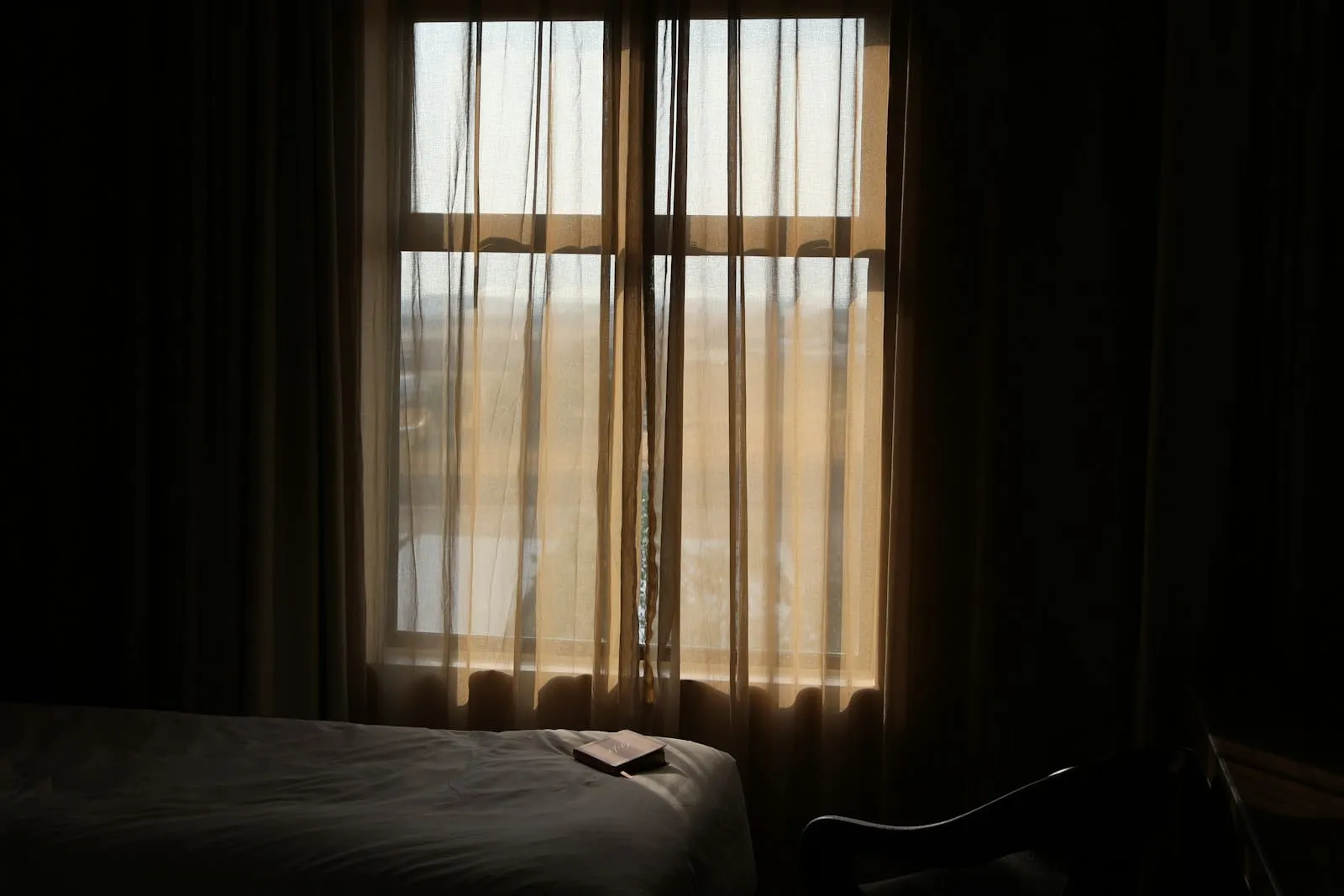 Daylight through a curtained window in an otherwise dark room.