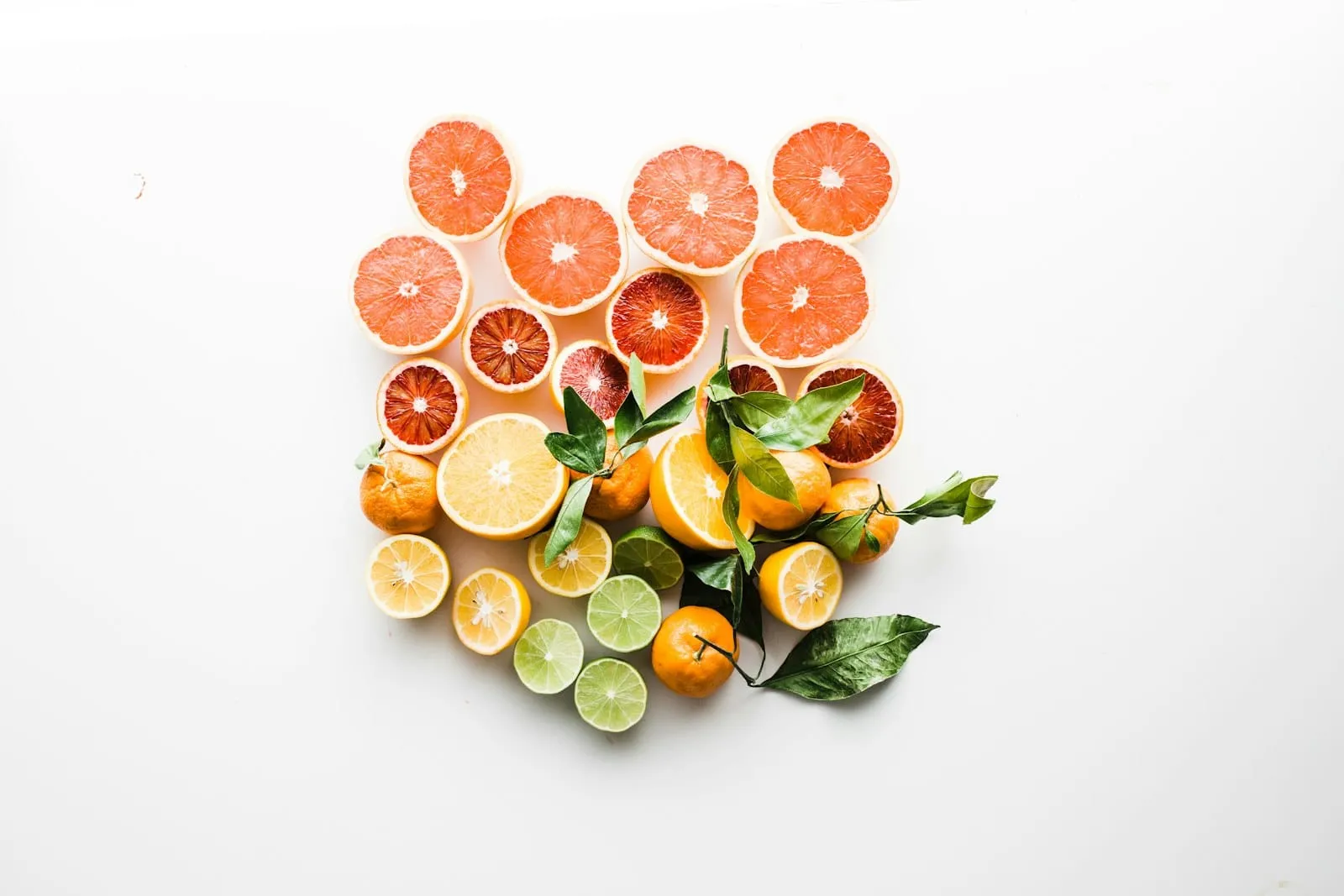Halved and whole citrus fruit arranged on a white surface.